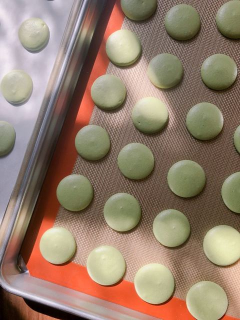 Macaron shells cooling on a baking tray
